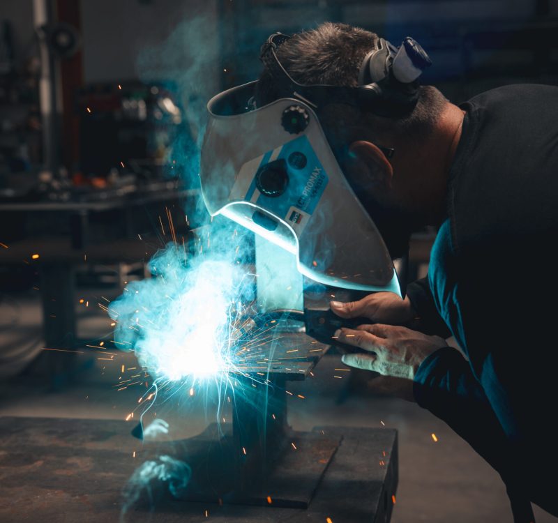 Saldatore al lavoro con maschera in officina